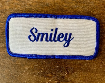 Smiley. A white work shirt patch that says "Smiley" in blue script with blue border