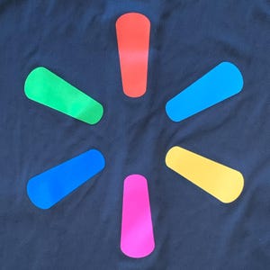 May include: A black background with a stylized starburst design. The starburst is made of six colorful points: green, red, blue, yellow, pink, and blue. The points are arranged in a starburst pattern.