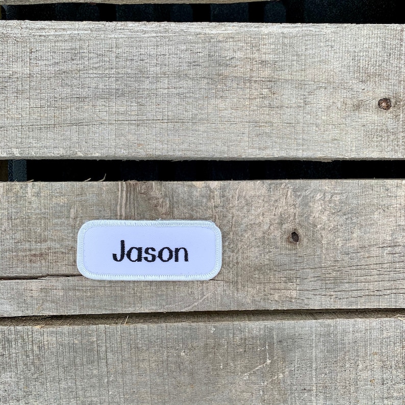 A white work shirt name patch that says Jason in print script Jason