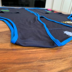 May include: A black sleeveless shirt with blue trim around the armholes and bottom hem. The shirt is made of a breathable, mesh fabric.