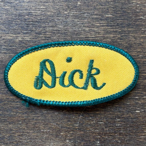 Dick - A yellow work shirt name patch that says "Dick" in green script with green border