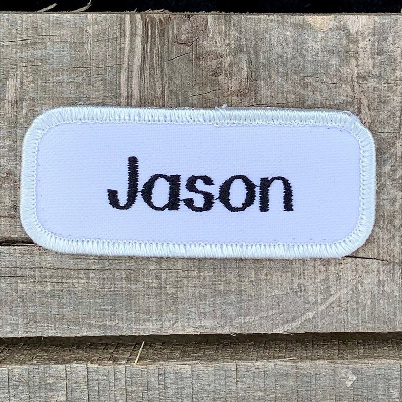 A white work shirt name patch that says Jason in print script Jason