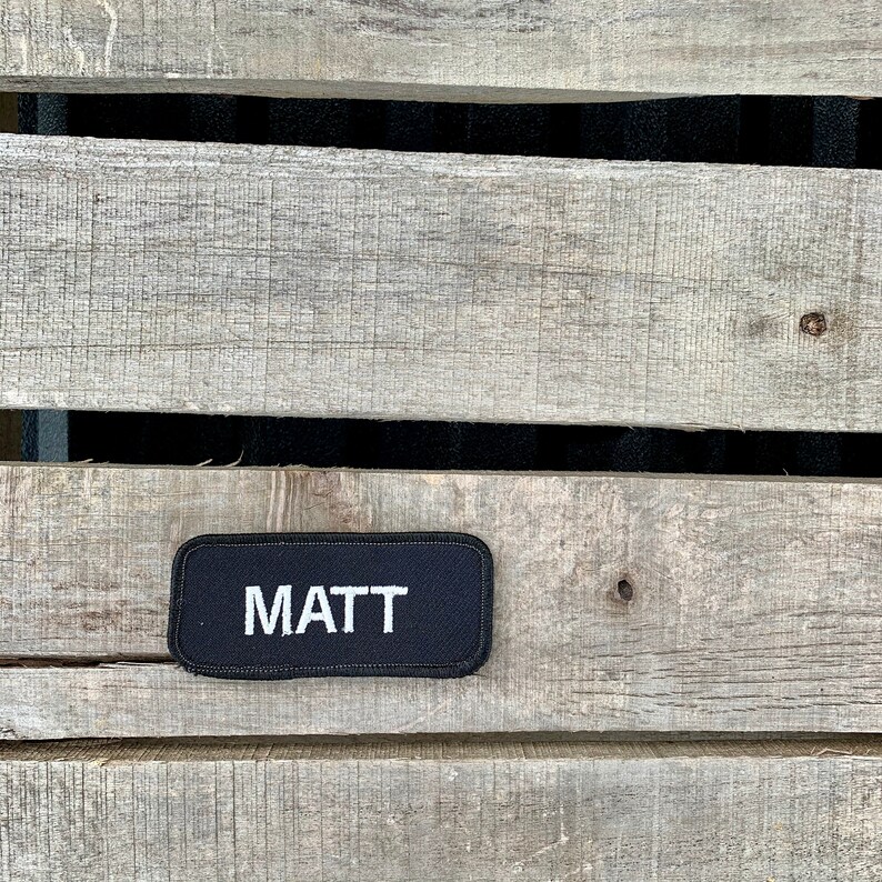 Matt A black work shirt patch that says Matt in white print