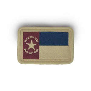 May include: Rectangular patch featuring a flag design with a tan border. The flag has a blue stripe, a tan stripe, and a maroon square with a white star and the dates "MAY 20th 1775" and "MAY 20th 1861".