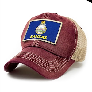 May include: A maroon baseball cap with a tan mesh back. The front of the cap features a rectangular patch with the Kansas state flag and the word "KANSAS" in yellow lettering. The cap has a curved brim and a structured crown.