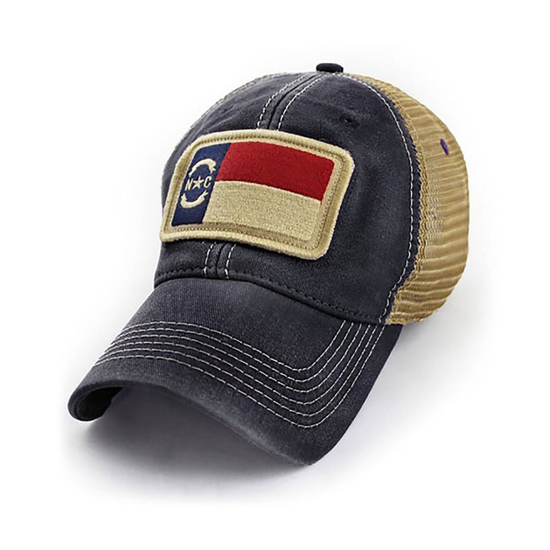 May include: A navy blue and tan trucker hat with a patch featuring the North Carolina state flag. The patch has a red, white, and tan color scheme and the letters "N.C." in a circle.