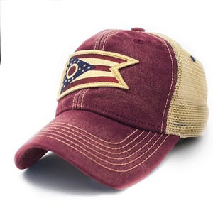 May include: A maroon baseball cap with a mesh back and a curved brim. The front of the cap features a patch with the Ohio state flag. The cap has a distressed look.