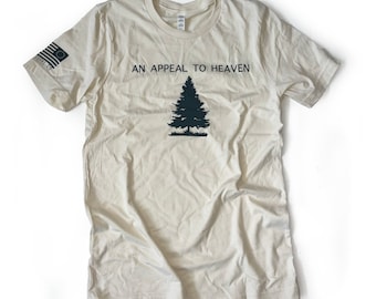 Puede incluir: Camiseta color crema con el texto "AN APPEAL TO HEAVEN" sobre un gráfico de pino verde oscuro. La manga izquierda presenta un pequeño diseño de la bandera estadounidense. La camiseta está hecha de un material suave y ligero.