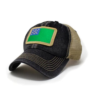 May include: A black and tan trucker hat with a green and blue flag patch. The hat has a curved brim and a mesh back. The flag patch is rectangular with a green background and blue stars. The hat is made of a durable fabric.