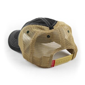 May include: A black and tan trucker hat with a mesh back. The hat has a red label with the text "SO REVIVAL" on the back.