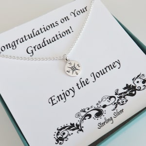 May include: A silver necklace with a compass charm and a card that reads "Congratulations on your Graduation! Enjoy the Journey" and "Sterling Silver".