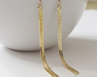 May include: A pair of long gold dangle earrings with a chain link design.
