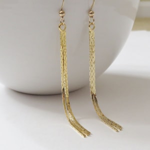 May include: A pair of long gold dangle earrings with a chain link design.