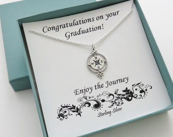 May include: A silver compass necklace in a blue gift box with a white card that reads "Congratulations on your Graduation! Enjoy the Journey Sterling Silver".
