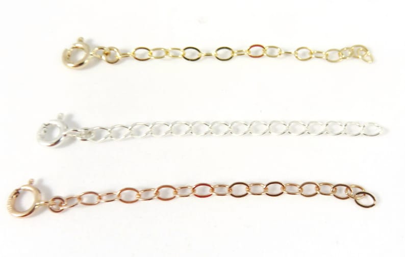 May include: Three gold, silver, and rose gold chain extenders with lobster clasps. The extenders are different lengths and styles.