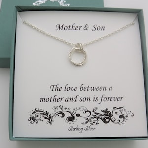 May include: A sterling silver necklace with two interlocking circles, presented in a teal gift box. The card inside reads "Mother & Son" and "The love between a mother and son is forever."