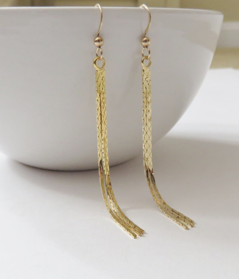 May include: A pair of long gold dangle earrings with a chain link design.