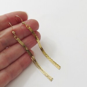 May include: A pair of long, gold-tone dangle earrings with a chain-link design.