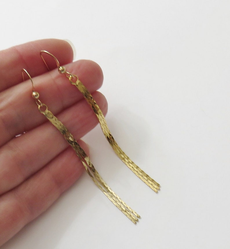 May include: A pair of long, gold-tone dangle earrings with a chain-link design.