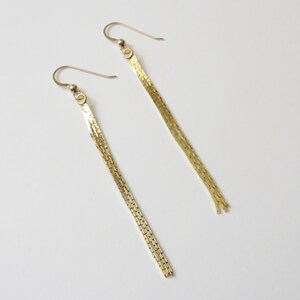 May include: A pair of gold dangle earrings with a chain link design.