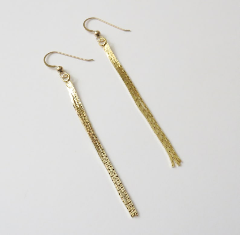 May include: A pair of gold dangle earrings with a chain link design.