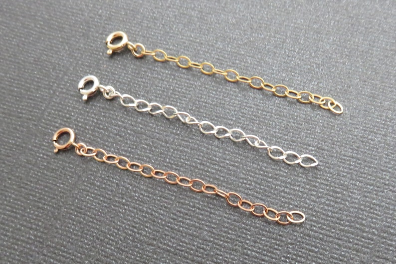May include: Three chain extenders in gold, silver, and rose gold. Each extender is approximately 5 cm long and has a lobster clasp.