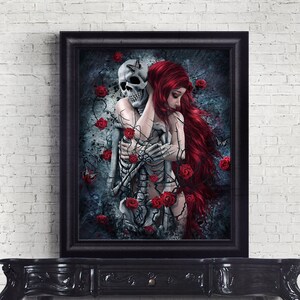 Op de afbeelding: Een ingelijst gotische kunstprint met een vrouw met lang rood haar die een skelet omarmt. De achtergrond is donkerblauw met rode rozen en vlinders.