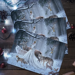 May include: Greeting cards featuring a winter forest scene with a woman in a white gown, deer, wolves, and other animals. The cards are on a wooden surface with Christmas decorations, including red ornaments, pine cones, and string lights.