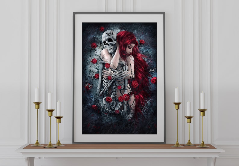 Op de afbeelding: Een ingelijst gotische kunstprint met een vrouw met lang rood haar die een skelet omarmt. De achtergrond is donker en heeft rode rozen en wijnstokken.
