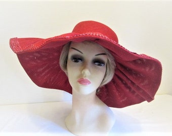 Pode incluir: Um chapéu vermelho de abas largas com uma trama texturizada, exibido em uma cabeça de manequim. O chapéu apresenta uma coroa arredondada e uma aba grande e flexível. A cor do chapéu é um vermelho profundo e vibrante.