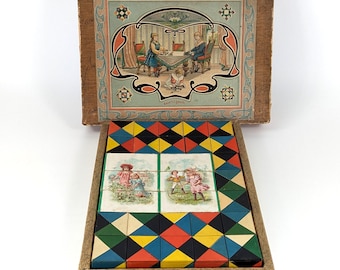 May include: Vintage wooden puzzle with a decorative lid featuring a family scene. The puzzle box contains colorful geometric blocks and picture tiles. The box is made of wood and has a rectangular shape.