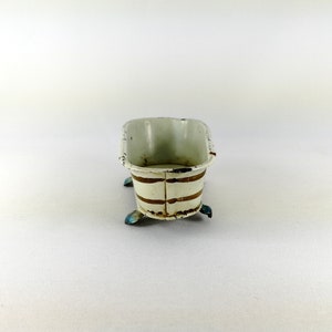 May include: A white enamel bathtub with gold stripes and blue feet. The bathtub is made of metal and has a vintage look.