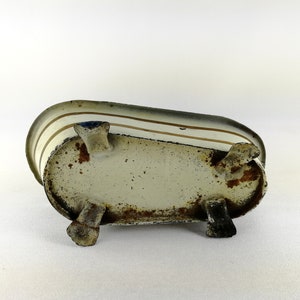 May include: A white metal bathtub with brown stripes and four legs. The bathtub is slightly rusted and has a vintage look.