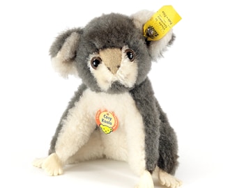 May include: A gray and white plush koala bear toy with a yellow tag that says "Steiff - Cosy Koala".