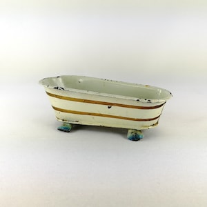 May include: A white metal bathtub with gold stripes and blue feet. The bathtub is a toy.