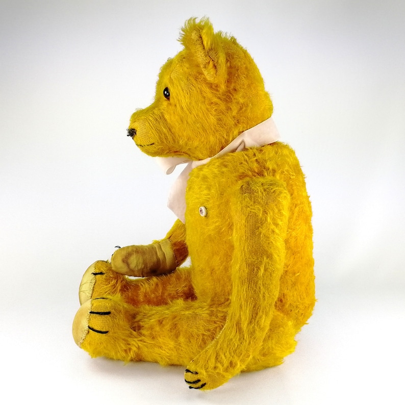 Vintage Petz teddy bear shown from the left side. The sturdy body and significant profile of the face are seen. 3 claws stitches on the feet and paws are partly visible.