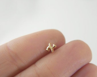 May include: A small gold-colored cat charm, shown on a finger.