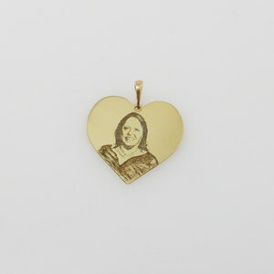 May include: A gold heart-shaped pendant with an engraved image of a person.