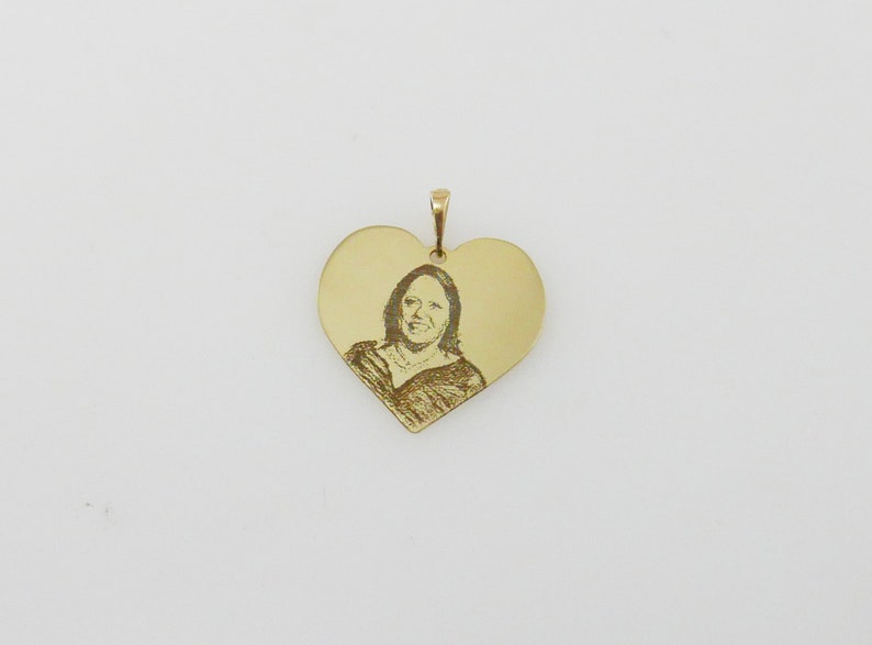 May include: A gold heart-shaped pendant with an engraved image of a person.