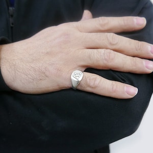 Könnte beinhalten: Ein silberner Siegelring mit einem erhabenen Buchstaben 'A' auf der Vorderseite.