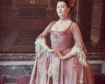 Peut inclure: Une femme vêtue d'une robe rose avec des bordures en dentelle blanche et un chapeau à plumes blanches orné de fleurs roses. La robe est décorée de paillettes et de motifs floraux. Elle se tient dans une pièce avec un sol en marbre et un tableau en arrière-plan.