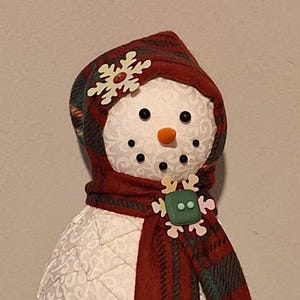 Festive Snowman with plaid scarf and hat and coordinating pom pom, button, and sequins. Various colors available.