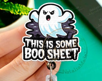 Könnte beinhalten: Ein weißer Geist mit schwarzem Umriss und wütenden Augen fliegt vor einem schwarz-weißen Hintergrund. Der Text "This is some Boo Sheet" steht unter dem Geist. Das Bild zeigt einen Badge-Reel mit einem silbernen Clip.