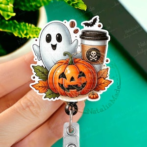 May include: A Halloween-themed badge reel with a ghost, a pumpkin, a coffee cup with a skull and crossbones, and fall leaves. The reel is attached to a silver clip.