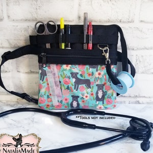 May include: A black medical fanny pack with a teal floral print featuring dog illustrations. The pack has multiple pockets holding scissors, pens, and other medical supplies. A stethoscope and tape are also visible. The text "**TOOLS NOT INCLUDED**" is displayed.