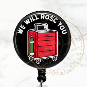 Peut inclure: Un porte-badge noir et rouge avec une image de dessin animé d'un chariot médical et le texte "We Will ROSC You".