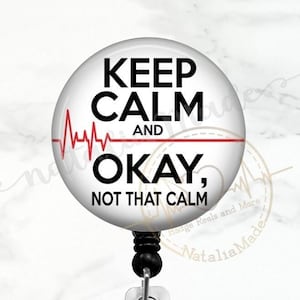 May include: A white round badge reel with a black retractable cord. The badge features a red heartbeat graphic and the text "Keep Calm and Okay, Not That Calm".