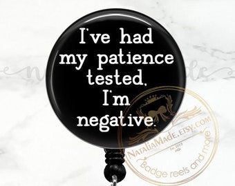 May include: Black and white badge reel with a black button and a clear plastic clip. The button has the text "I've had my patience tested. I'm negative."