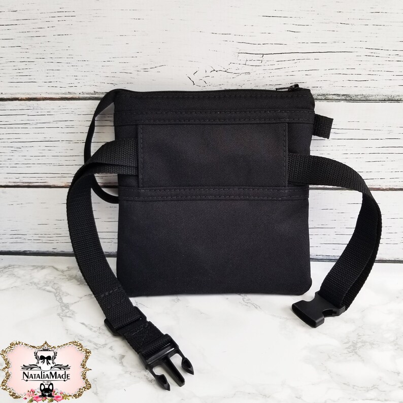 Op de afbeelding: Zwarte heuptas met een hoofdvak met ritssluiting en een verstelbare riem. De tas heeft een rechthoekig ontwerp met een kleiner voorvak en een zwarte plastic gesp. Gemaakt van duurzame stof.