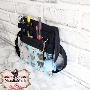 May include: A black and teal utility bag with a dog-themed pattern, featuring various tools and accessories. The bag has multiple compartments, including a section for scissors, pens, and a roll of tape. The bag is designed with a shoulder strap for easy carrying.